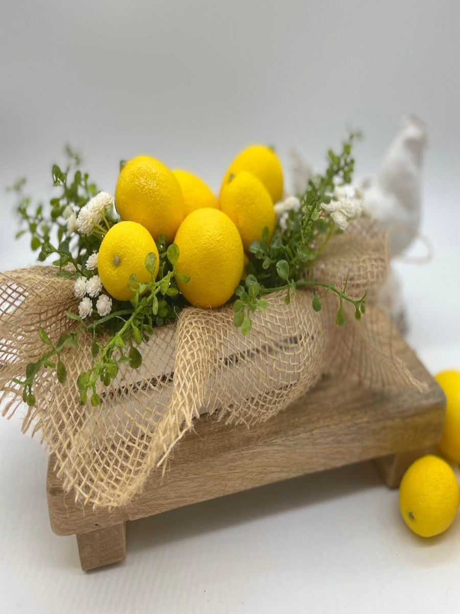 Artificial Lemons with greenery and delicate white flowers in white wooden crate decorated with burlap