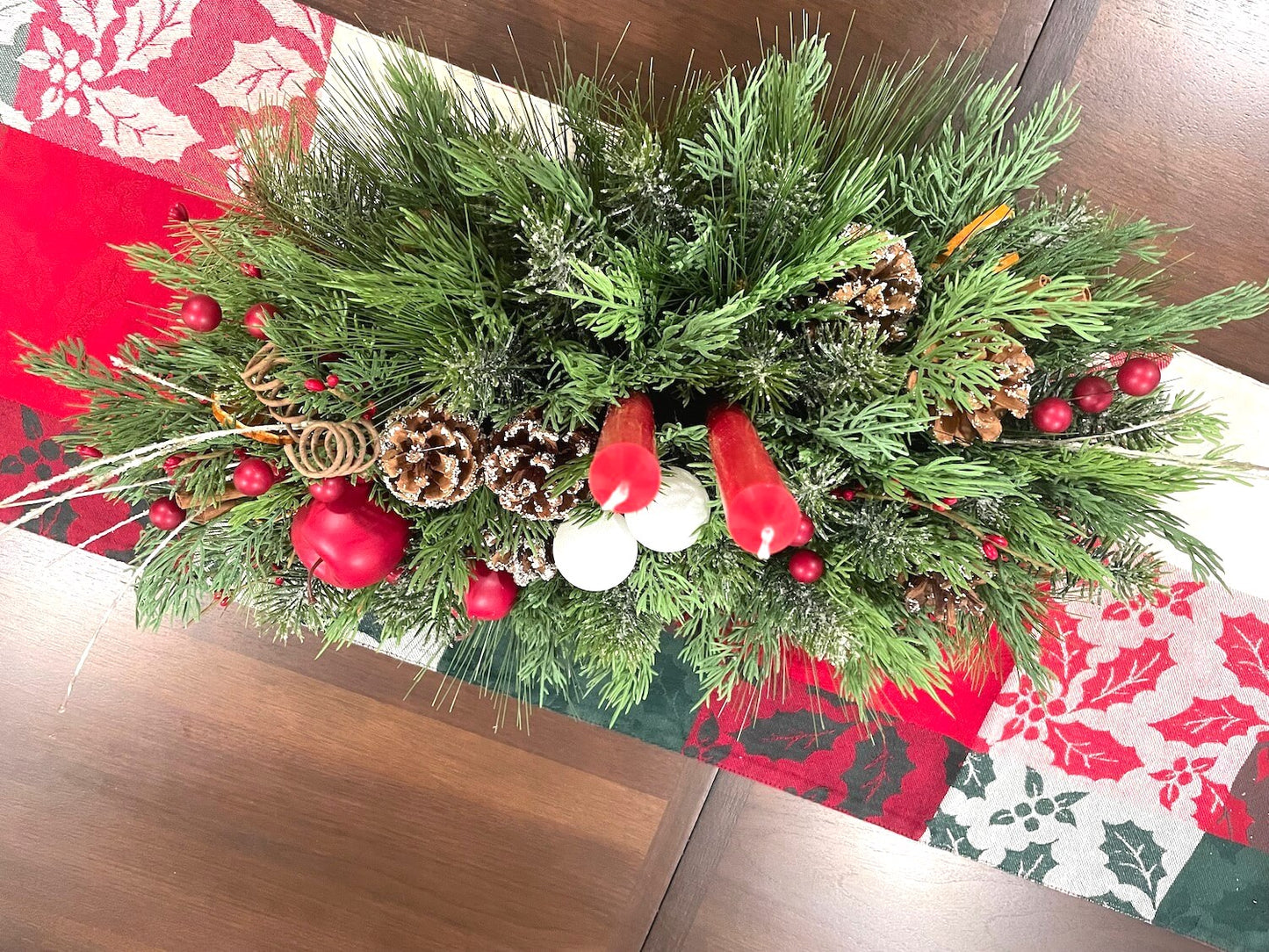 picture from top showing entire arrangement with variety evergreen and greenery, natural elements and 2 red candles, lush large and elegant