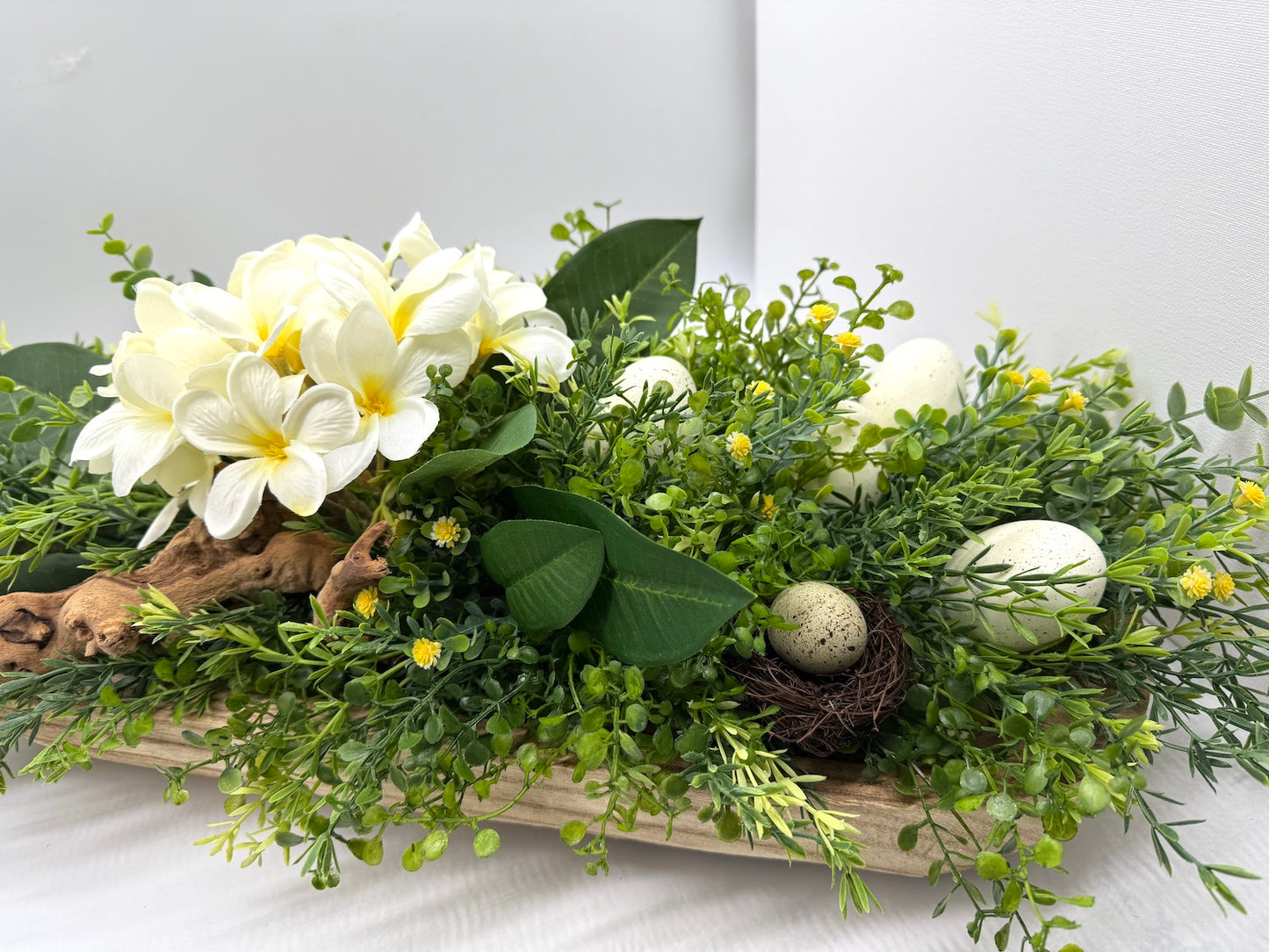 artificial greenery and flowers, and faux eggs, grapewood in long wooden planter all in modern farmhouse style