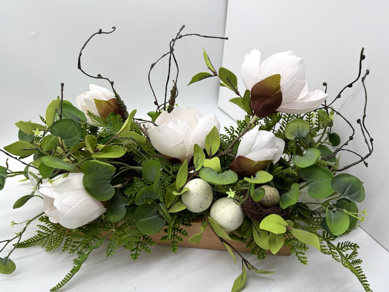 beautiful realistic magnolia flowers, artificial greenery, faux eggs in wooden planter easter arrangement
