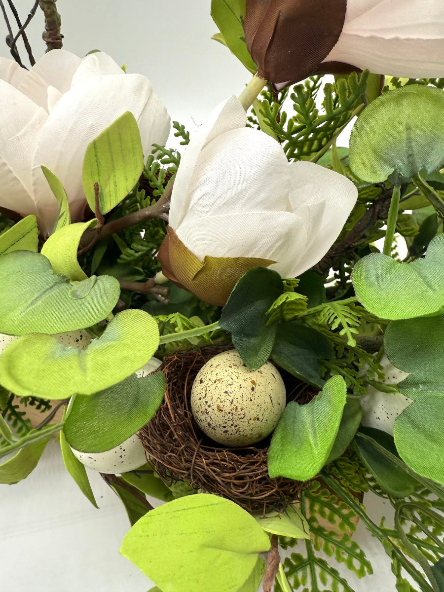 faux eggs in nest with realistoc looking greenery and fake flowers easter centerpiece
