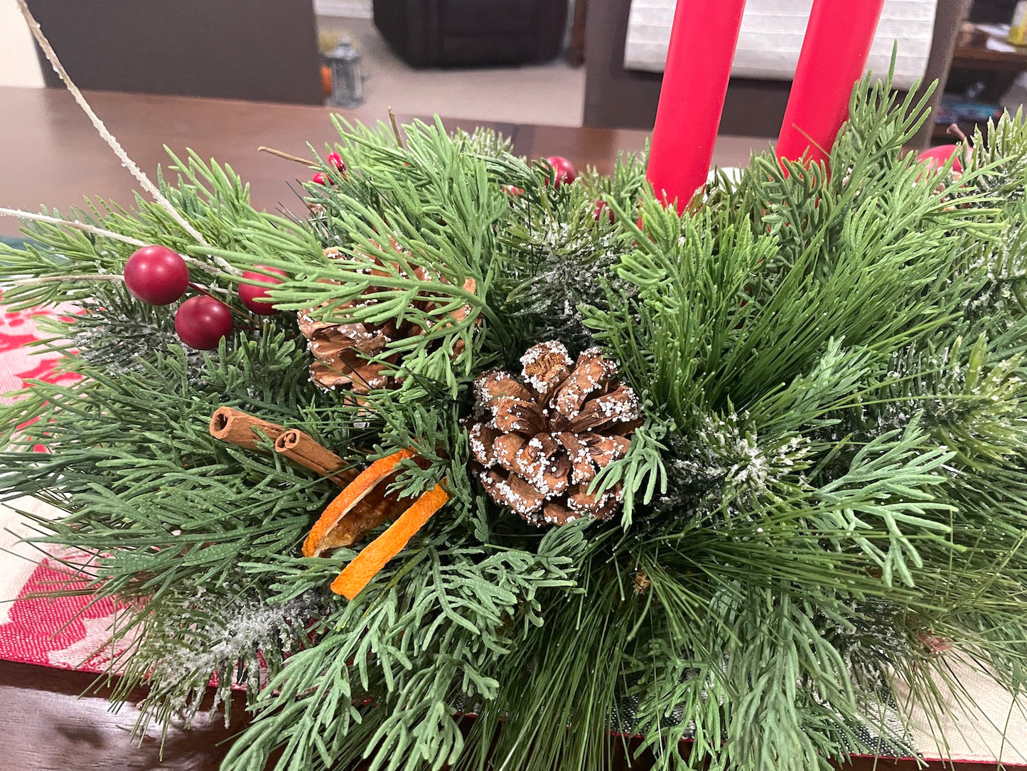 evergreen centerpiece with christmas ornaments, winter berries, pinecones, apples, cinnamon sticks and candles