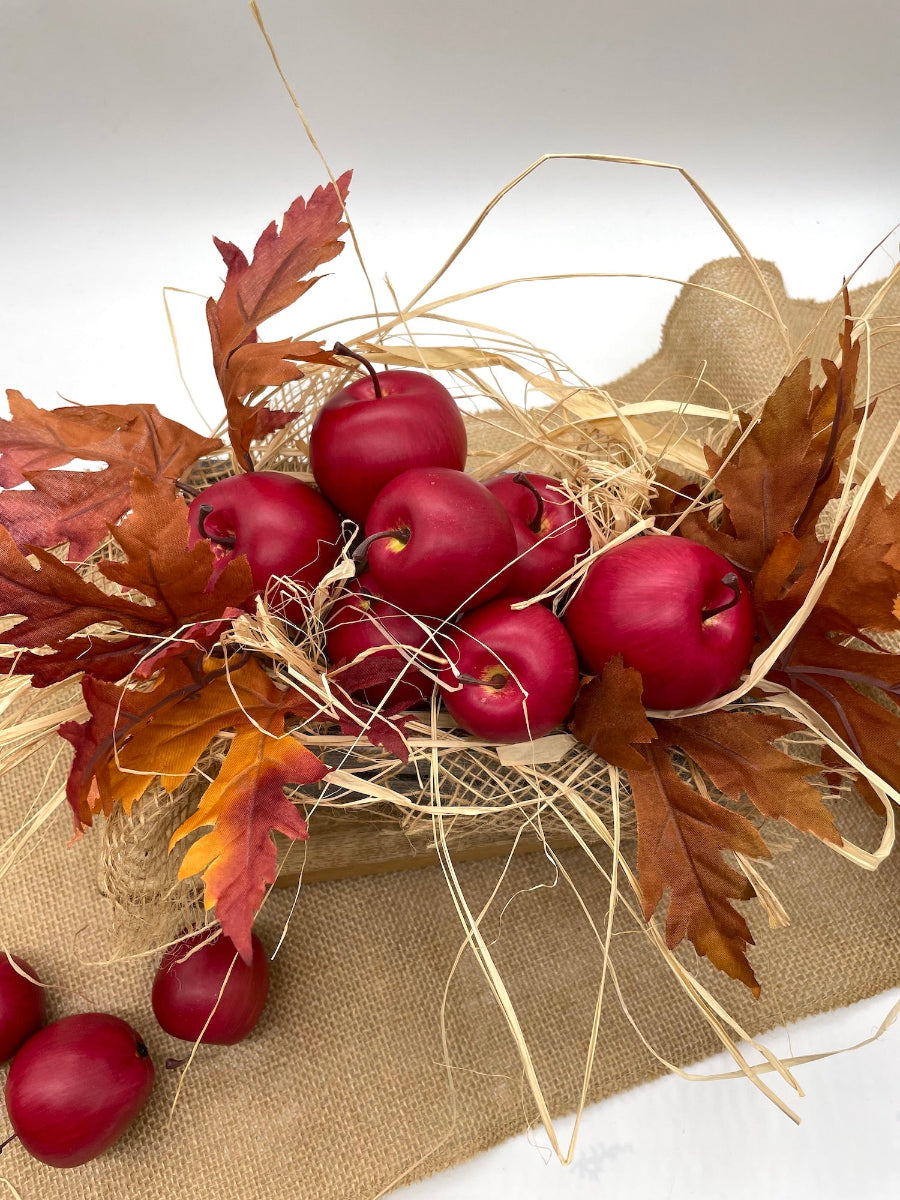 harvest arrangement of red apples and autumn leaves, raffia and burlap in wooden crate