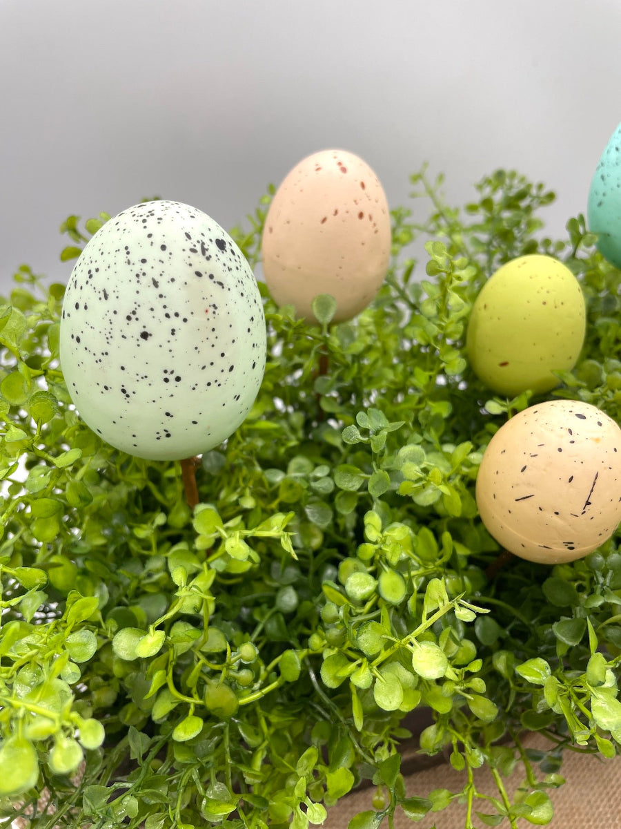 easter centerpiece with artificial greenery and faux eggs in wooden planter