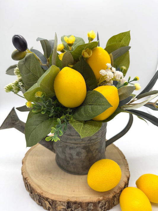 farmhouse arrangement with lemons, greenery and flowers in metal watering can
