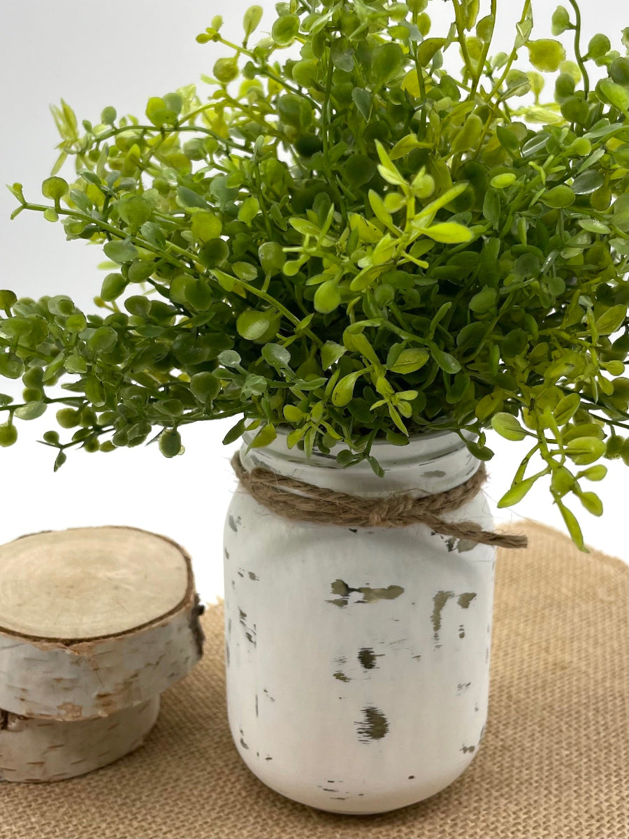 vivid faux greenery in mason jar painted in white and distressed and decorated with jute