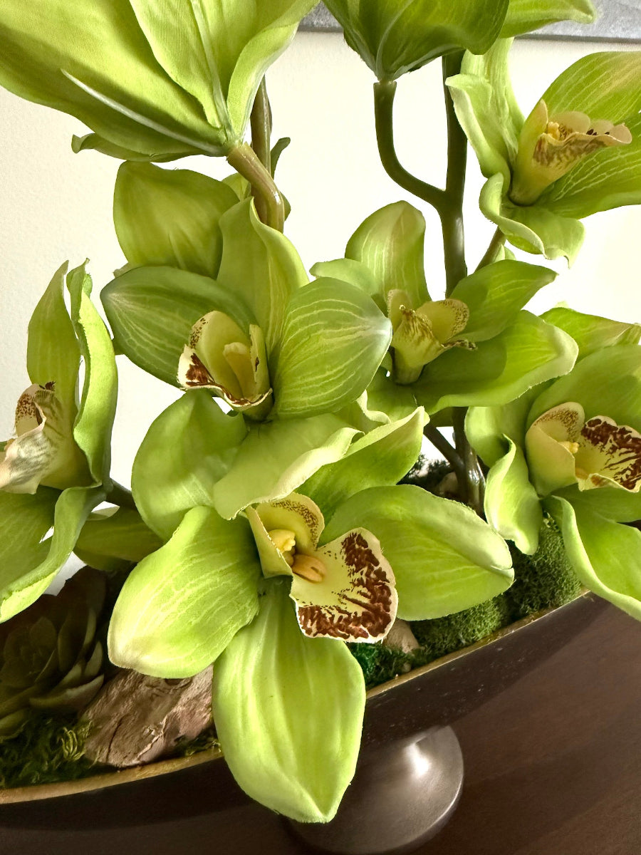 lifelike green orchid flowers in metal oval vase in dark copper color