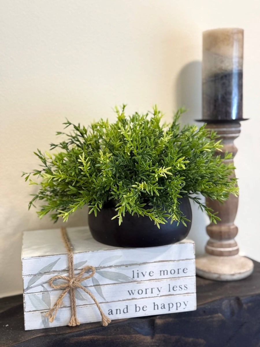 realistic looking faux plant of few shades of green placed in low black ceramic pot vase