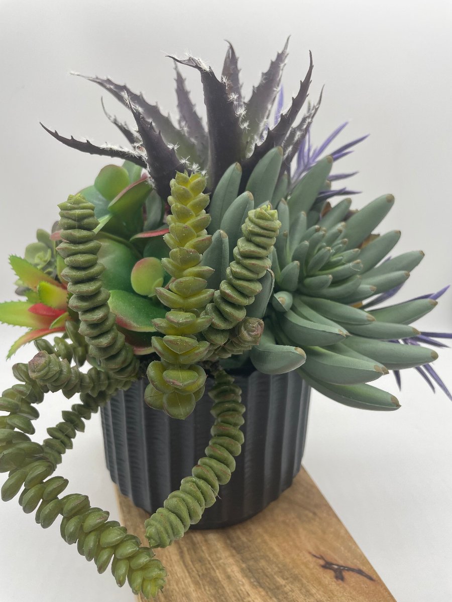 Faux Succulent Centerpiece-mix f variety of succulents in different shapes and style in variety of green to burgundy and purple, all set in textured black ceramic pot vase