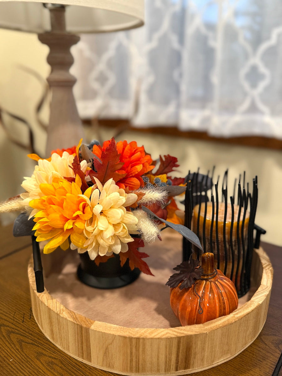 fall arrangement with flowers, leaves, pumpkins in orange and blue in black vase