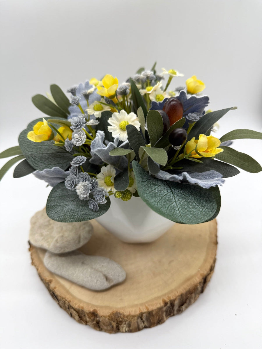 small artificial floral arrangement in whote ceramic vase