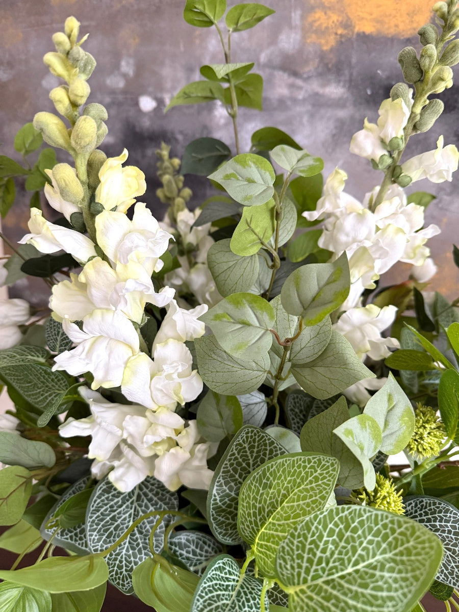 realistic fresh looking greenery stems and white flowers in elegant gold vase