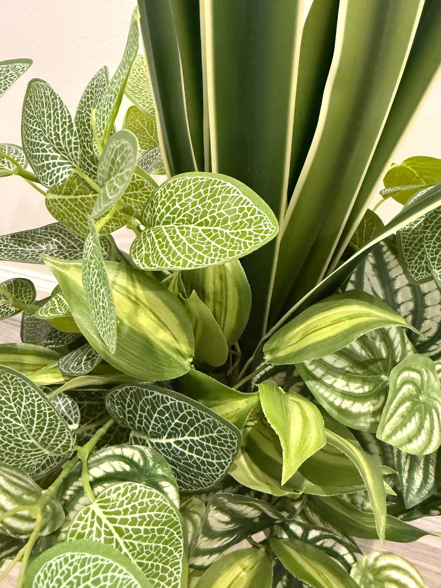 mix of greenery in different green tons and white touches in tall white ceramic vase