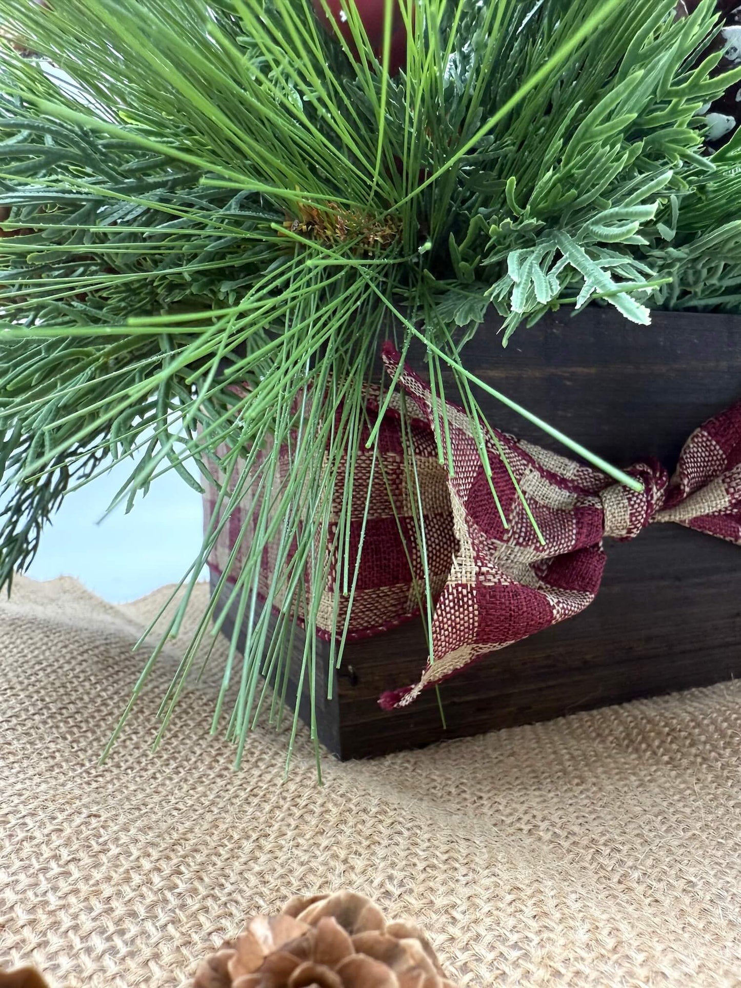 christmas arrangement with greenery, burgundy flowers, winter accents in wooden vase