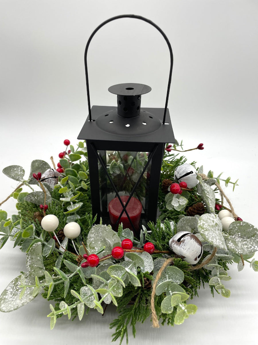evergreen small table wreath with winter greenery and red berries and bells with black metal lantern