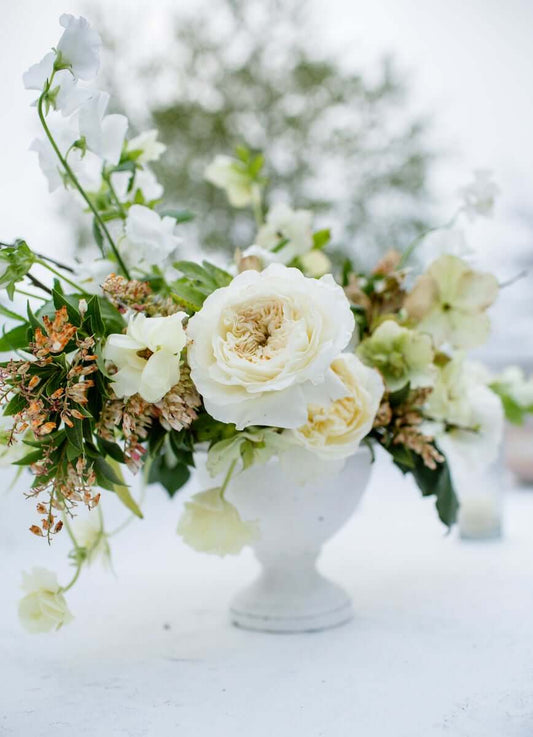 white flower arrangement with greenery in elegant vase