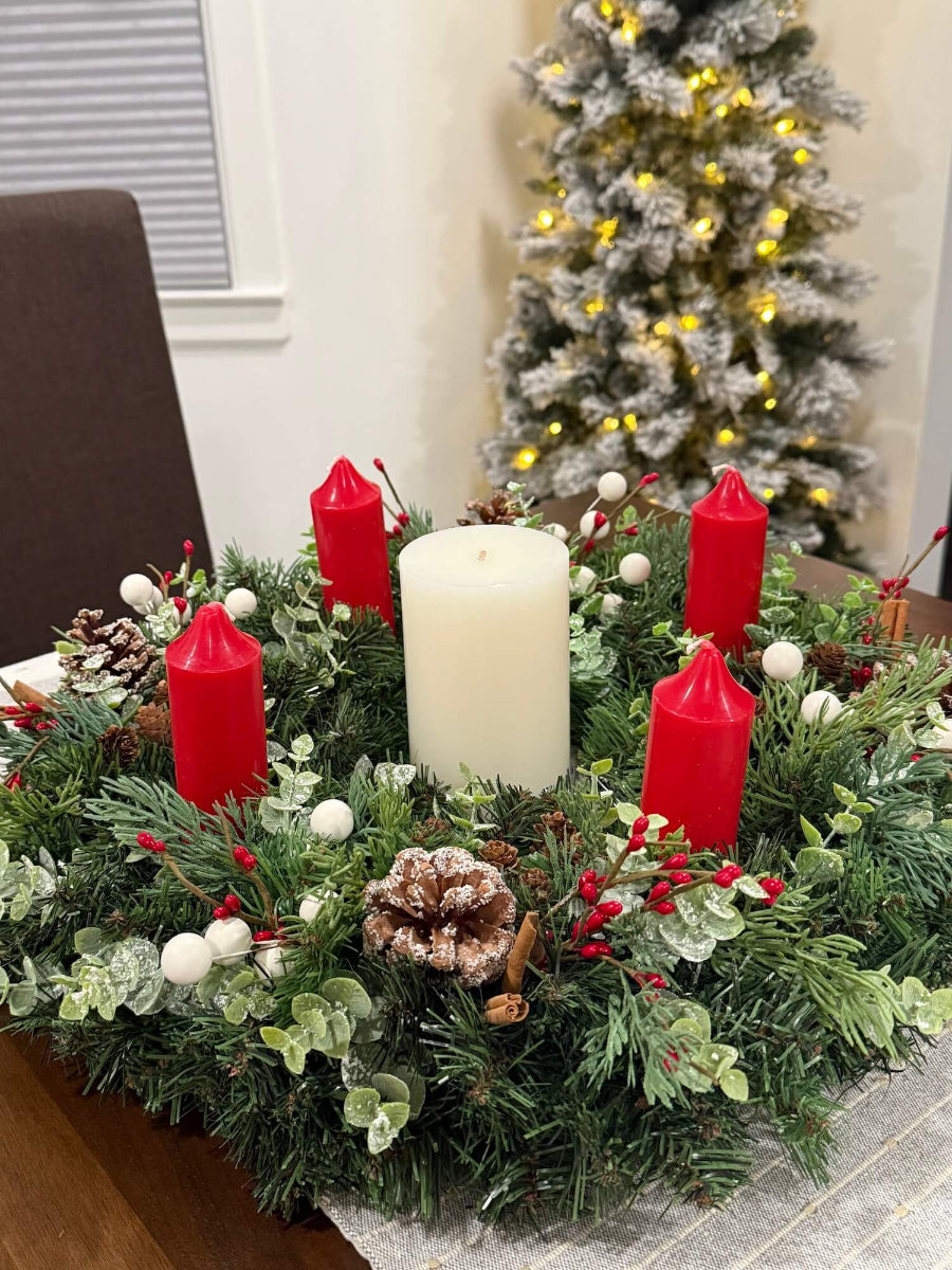 lush elegant handmade advent wreath with pine, arborvitae and snowy eucalyptus stems, with snowy and plain pinecones, cinnamon sticks, red and white berries, with short thick candles or purple/pink candles set on dining table