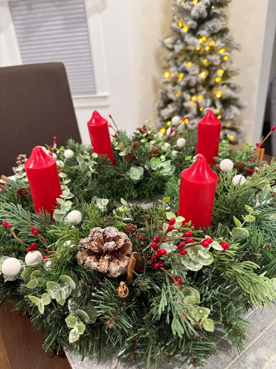 lush elegant handmade advent wreath with pine, arborvitae and snowy eucalyptus stems, with snowy and plain pinecones, cinnamon sticks, red and white berries, with short thick candles or purple/pink candles set on dining table