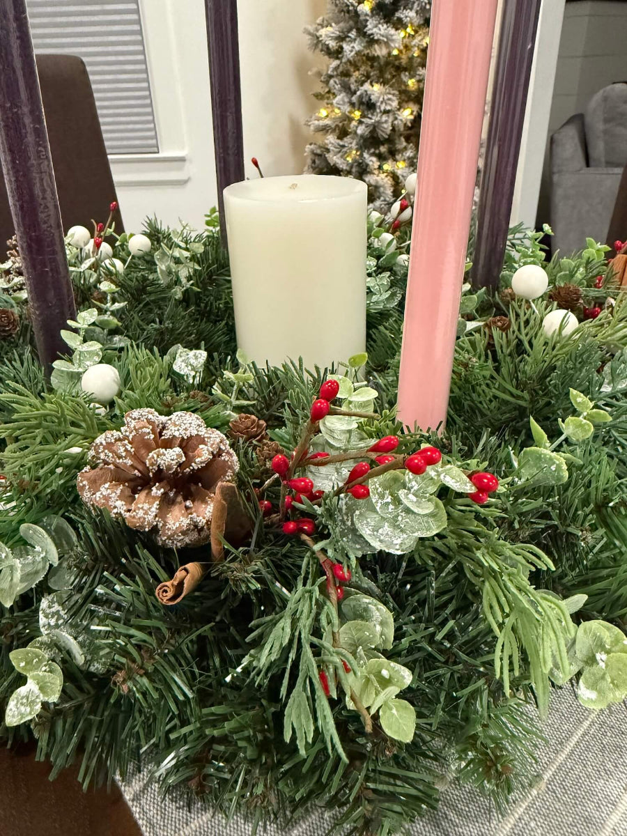 close up for handmade lush elegant evergreen advent wreath with arborvitae and snowy eucalyptus stems decorated with pinecones, red and white berries and cinnamon stick, with four taper candles in purple/pink, red or white perfect for dining table