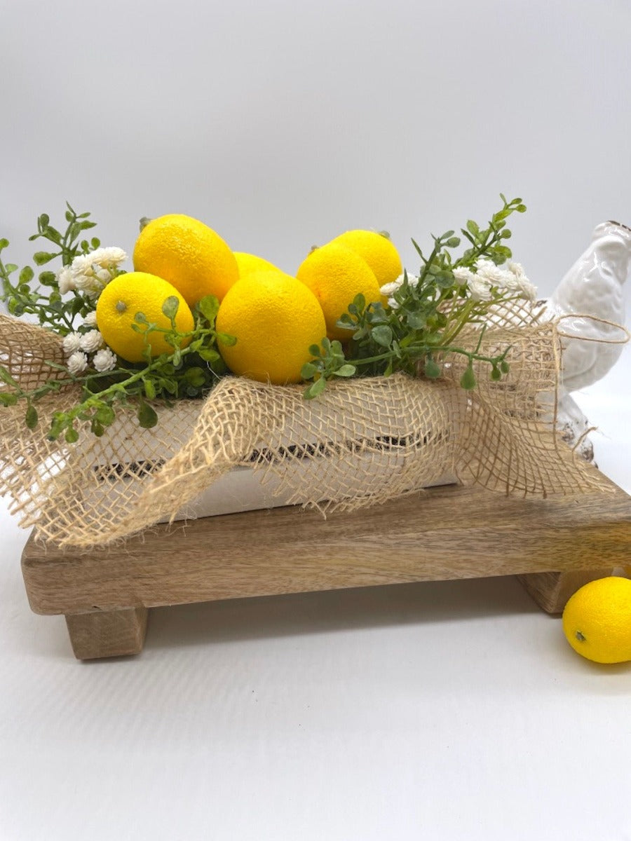 Artificial Lemons with greenery and delicate white flowers in white wooden crate decorated with burlap
