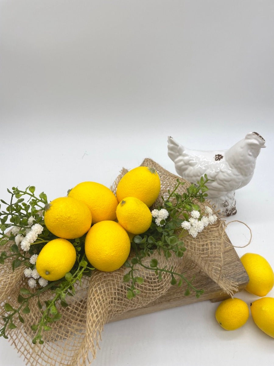view from top Artificial Lemons with greenery and delicate white flowers in white wooden crate decorated with burlap