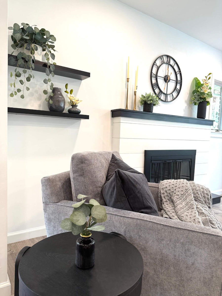 view of living room with faux plants and realistic looking silver dollar eucalyptus trailing in white textured ceramic pot