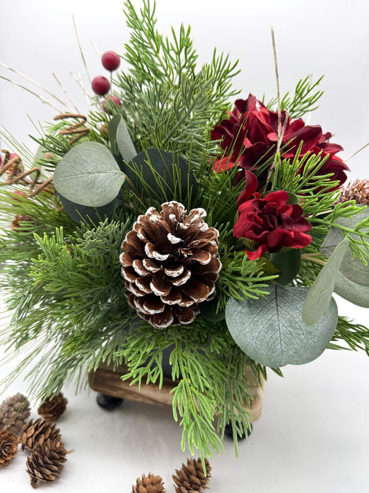 lush elegant evergreen and eucalyptus stem arrangement with deep red flowers, pinecones and winter accents