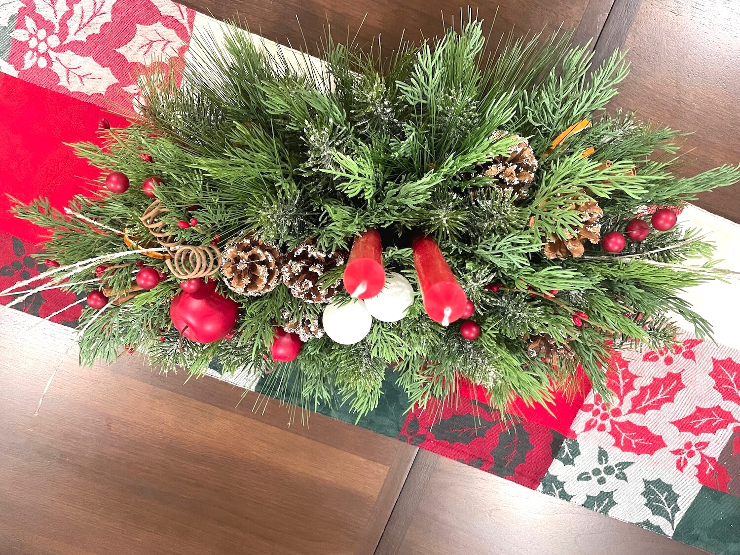 picture from top showing entire arrangement with variety evergreen and greenery, natural elements and 2 red candles, lush large and elegant