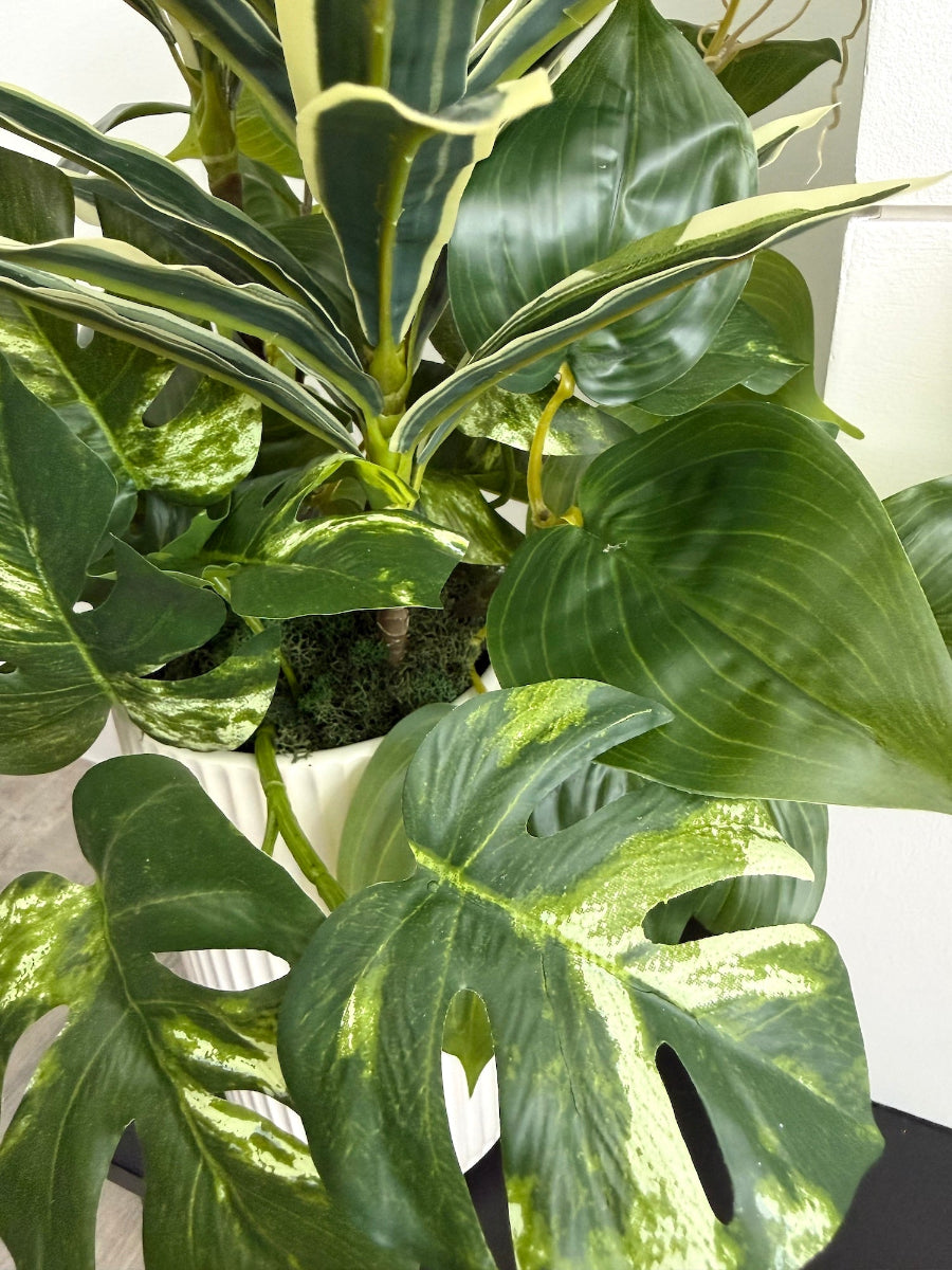 close up for tall arrangement, mix of 3 realistic looking vivid green faux plants with leaves in green and green-white, placed in tall white ceramic textured pot vase