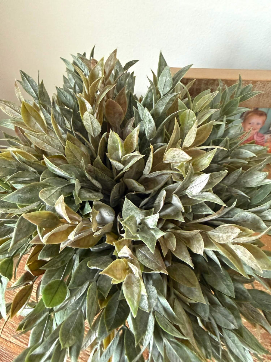 view from top close up for muted dusty green faux plant in yellow ceramic vase for table and shelf