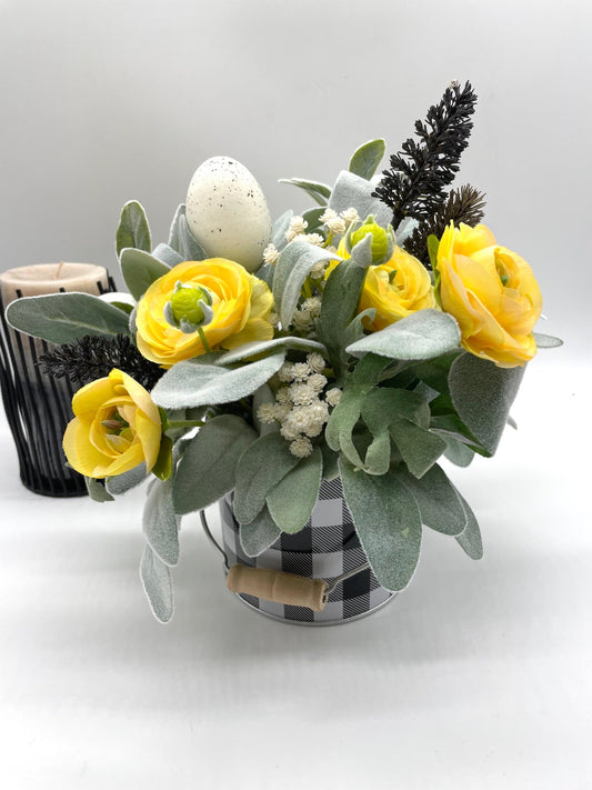 easter arrangement with labs ear, yellow flowers, white flowers and faux eggs in black white metal can vase