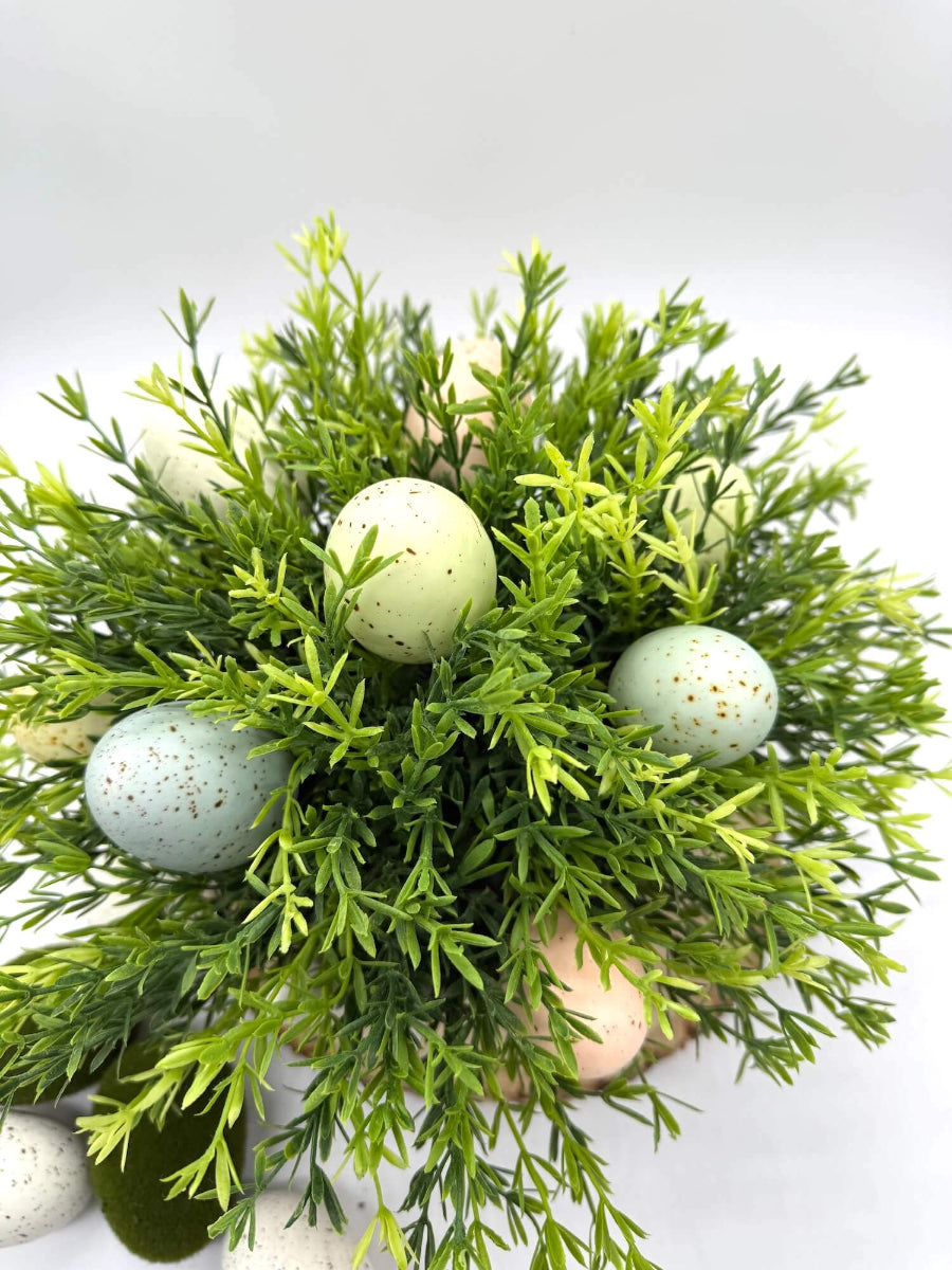 close up of faux greenery and easter eggs in ceramic bunny vase