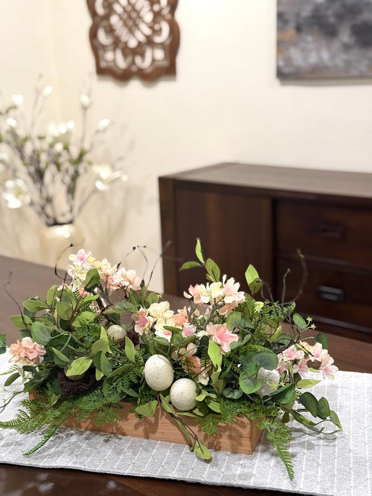 easter arrangement with greenery cherry blossom branches and faux eggs in wooden base