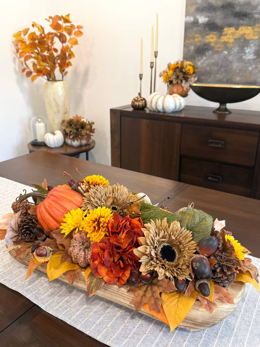 elegant rich in fall accents large fall centerpiece with flowers, pumpkin, leaves in orange, yellow, green, brown in long wooden vessel