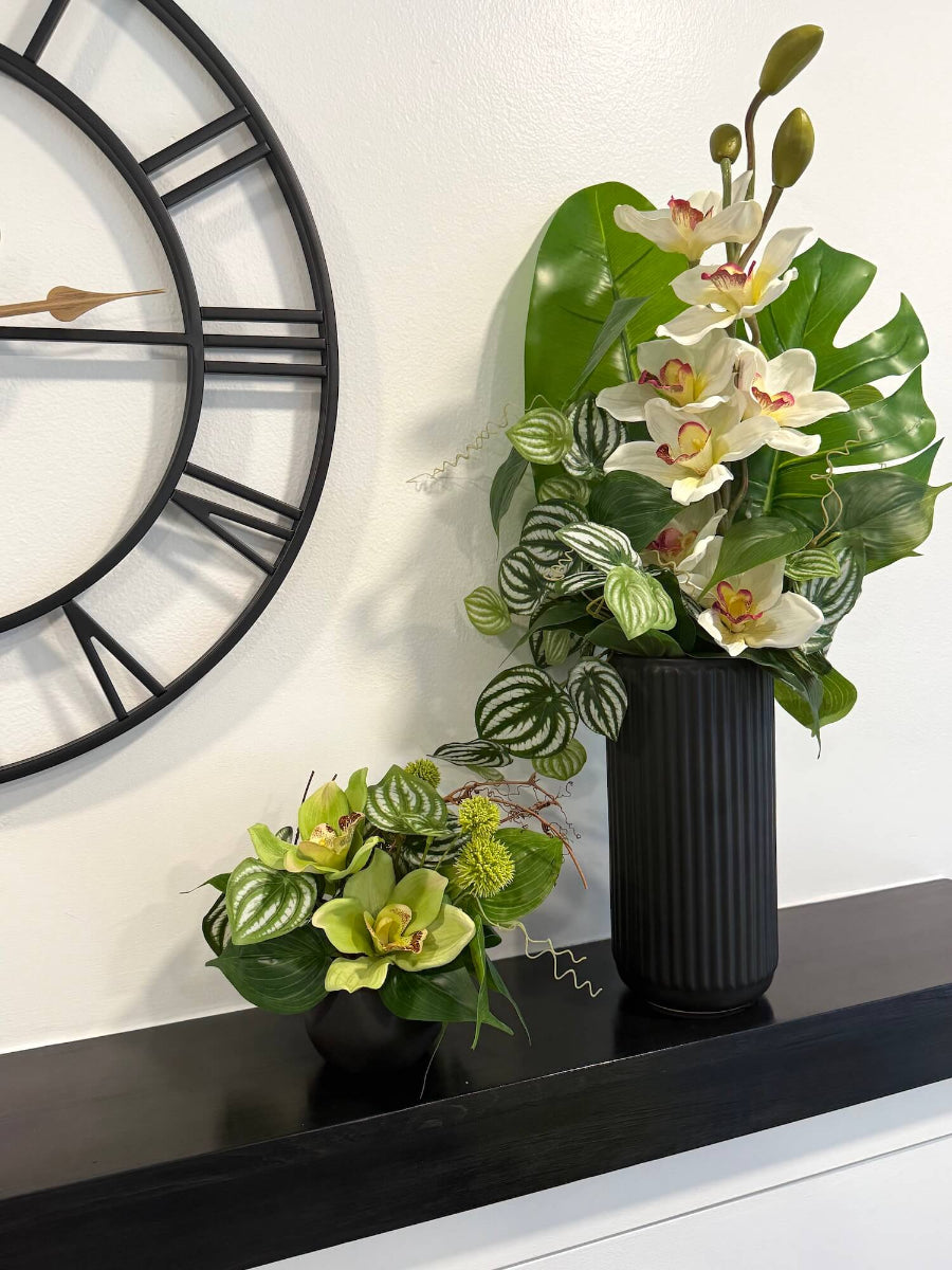 elegant  realistic orich arrangements with greenery in black ceramic vase