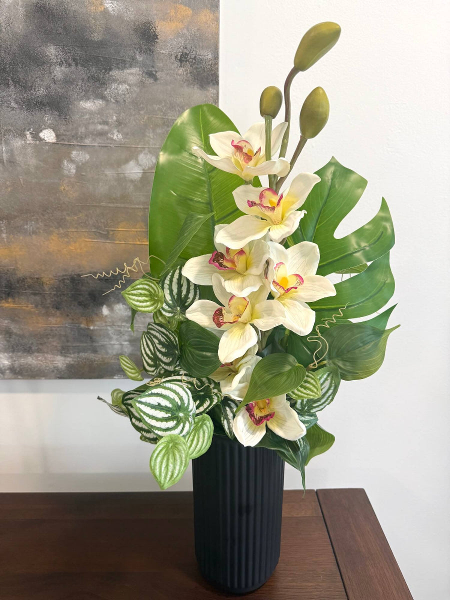 elegant realistic looking tall faux white orchid arrangement accompanied with greenery in matte black textured ceramic vase