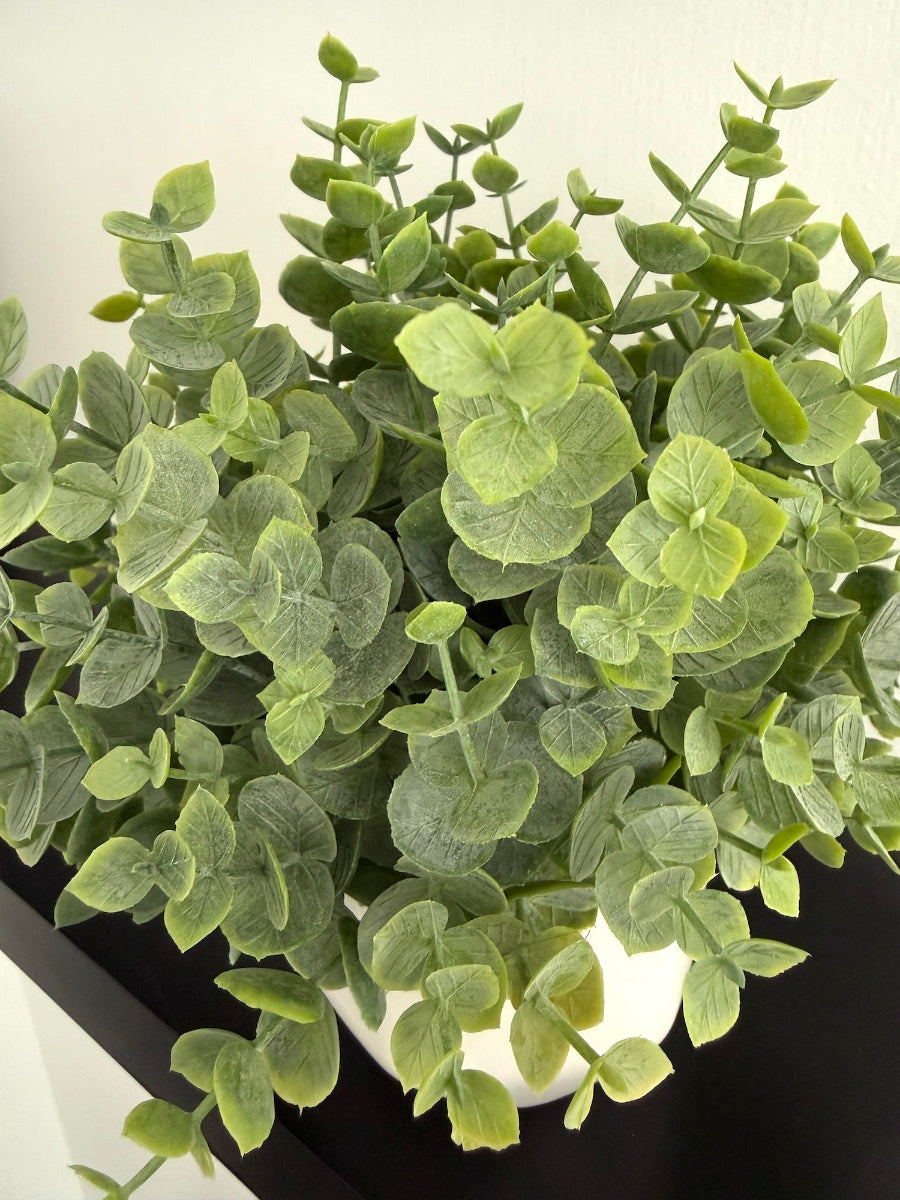 close up for faux eucalyptus arrangement in white ceramic vase pot