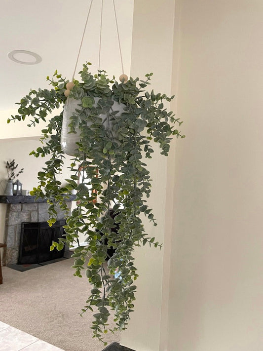 realistic faux eucalyptus plant with overlapping stems in hanging white ceramic pot on white strings
