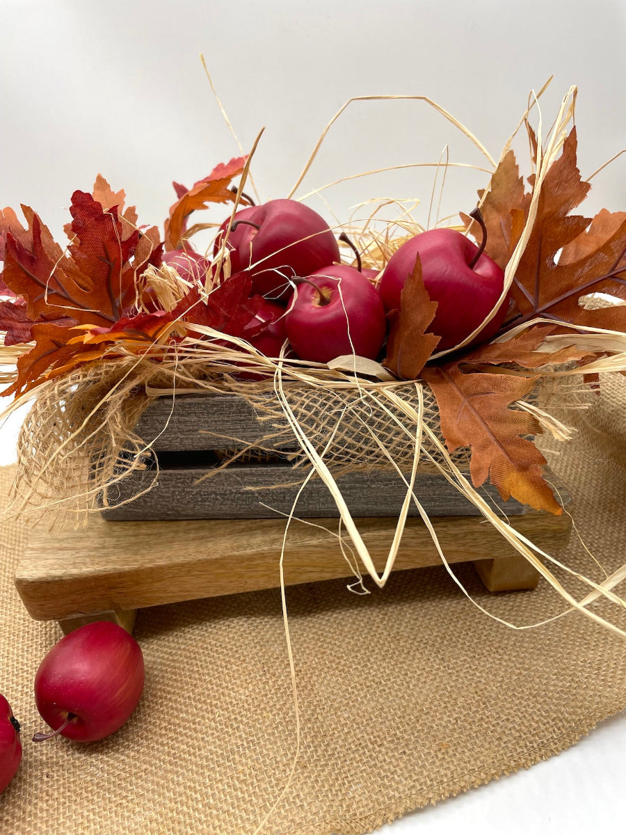farmhouse rustic arrangement with red apples, autumn leaves, and burlap in wooden crate