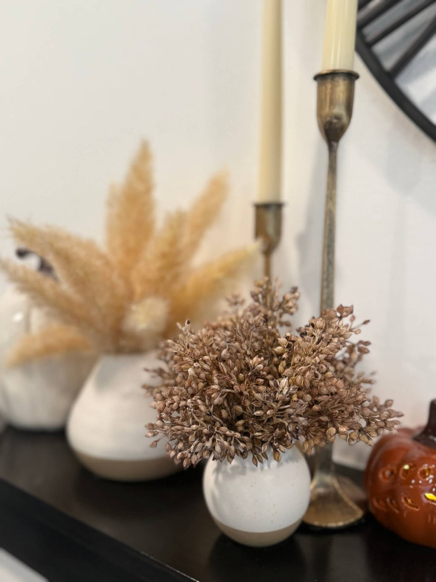 elegant lush realistic beige-brown wheat arrangement is small ivory beige vase on mantel shelf