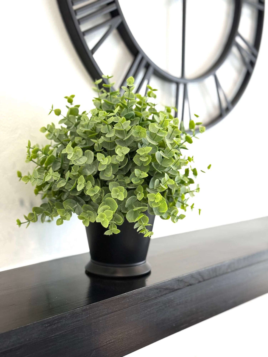 realistic looking faux eucalyptus in balck ceramic vase on mantel shlef