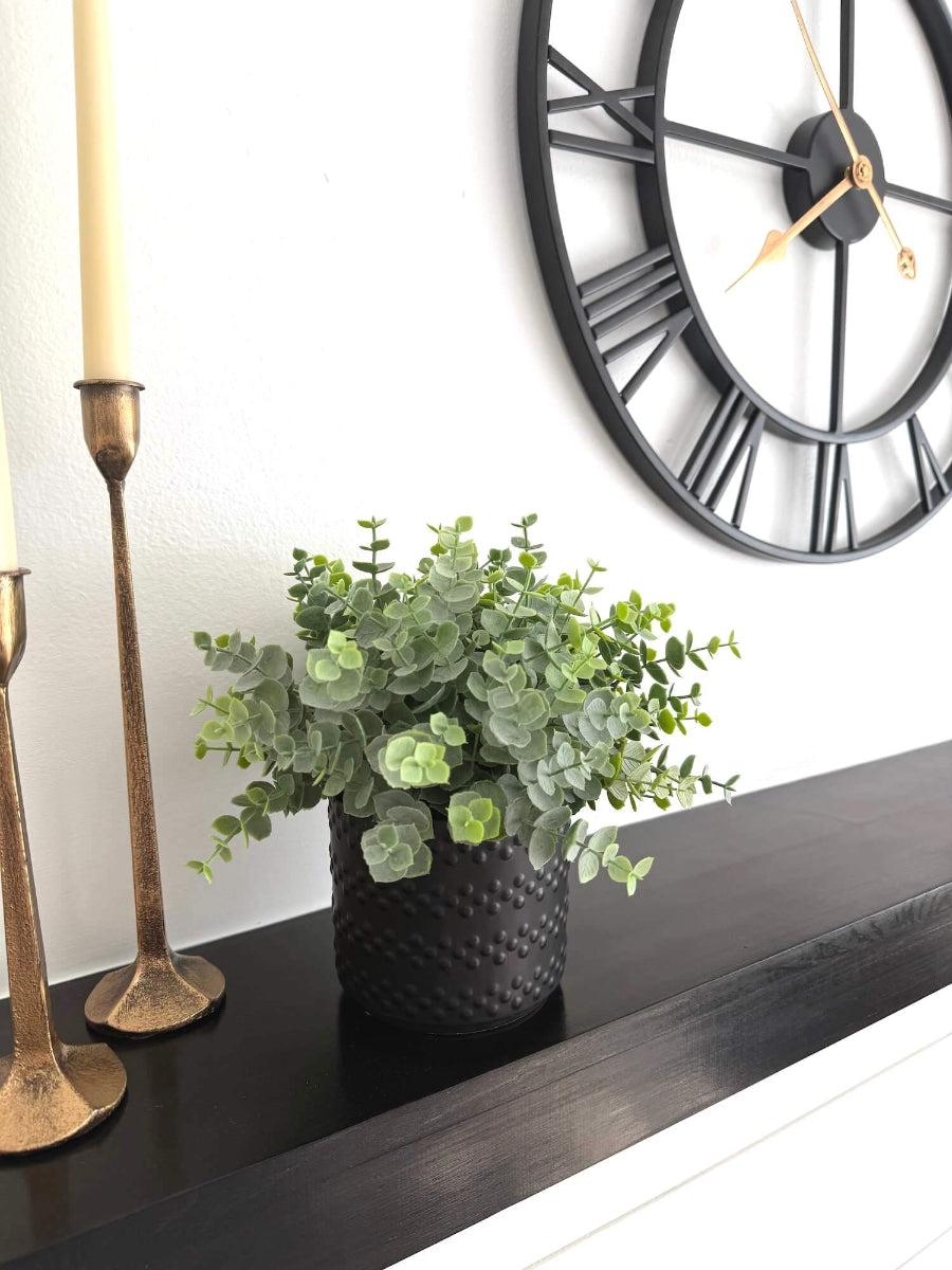 realistic looking green faux eucalyptus plant in elegant textured black matte ceramic pot 