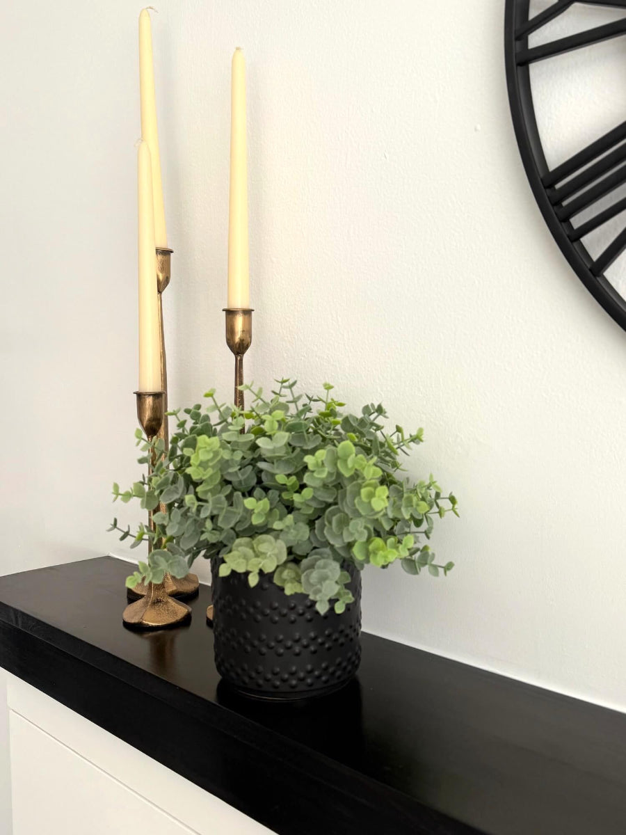 realistic looking green faux eucalyptus plant in elegant textured black matte ceramic pot 