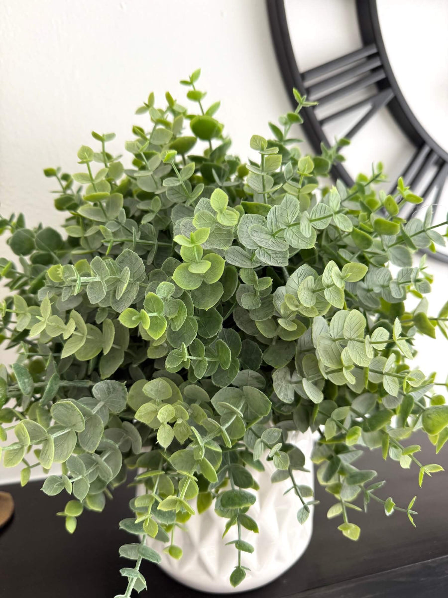 close up for realistic faux eucalyptus plant in white ceramic pot vase of diamond pattern