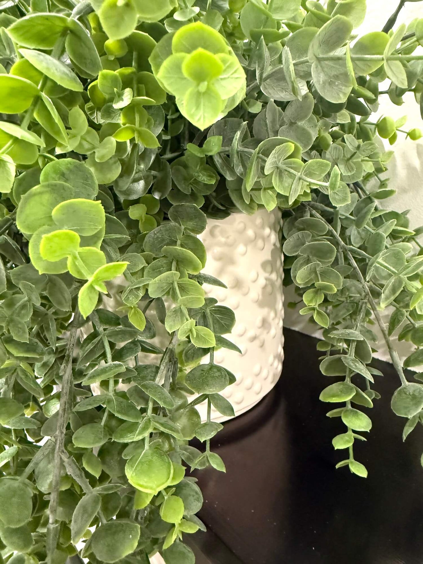 Close-up of a potted faux plant in ceramic white vase