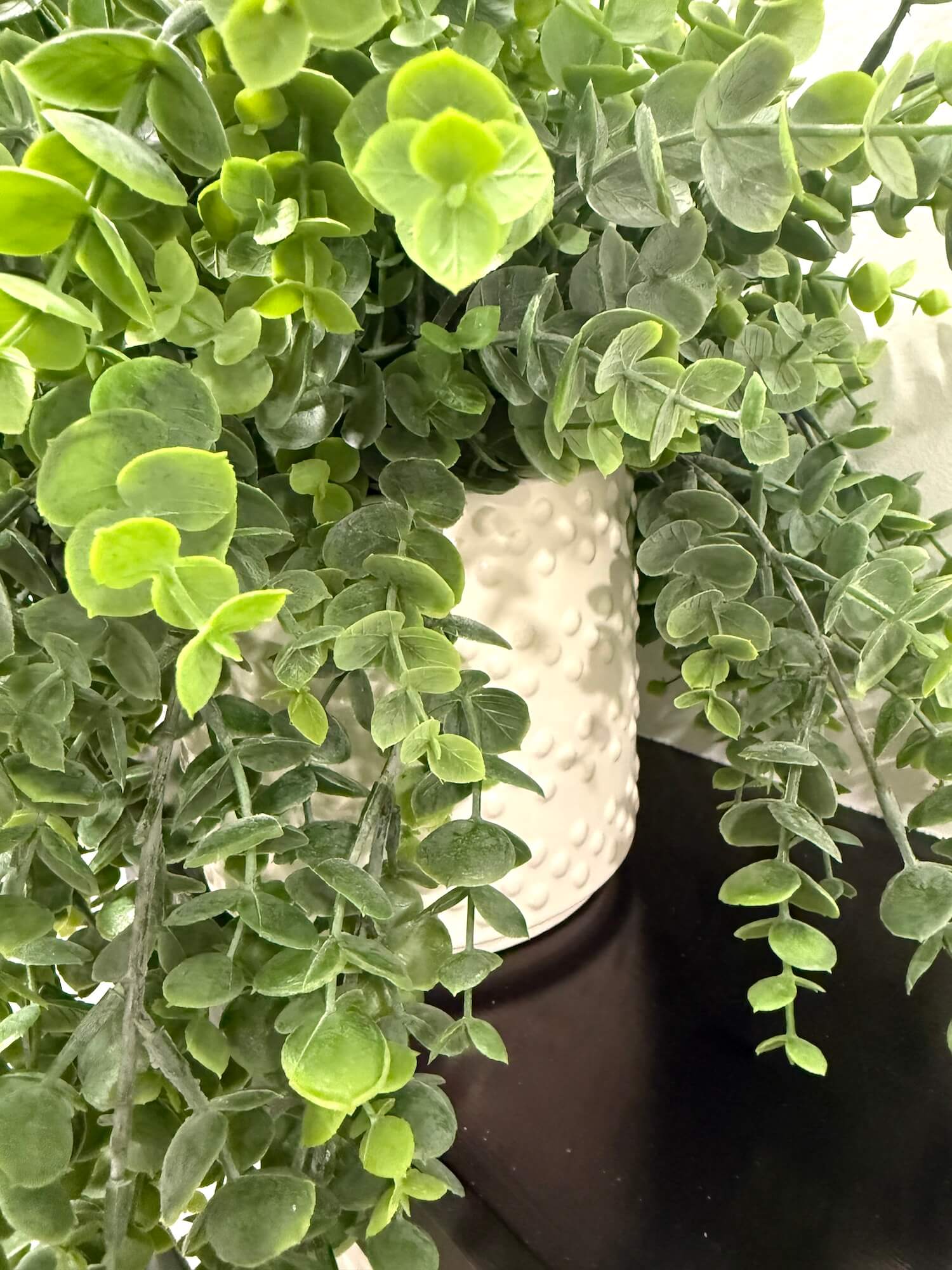 Close-up of a potted faux plant in ceramic white vase