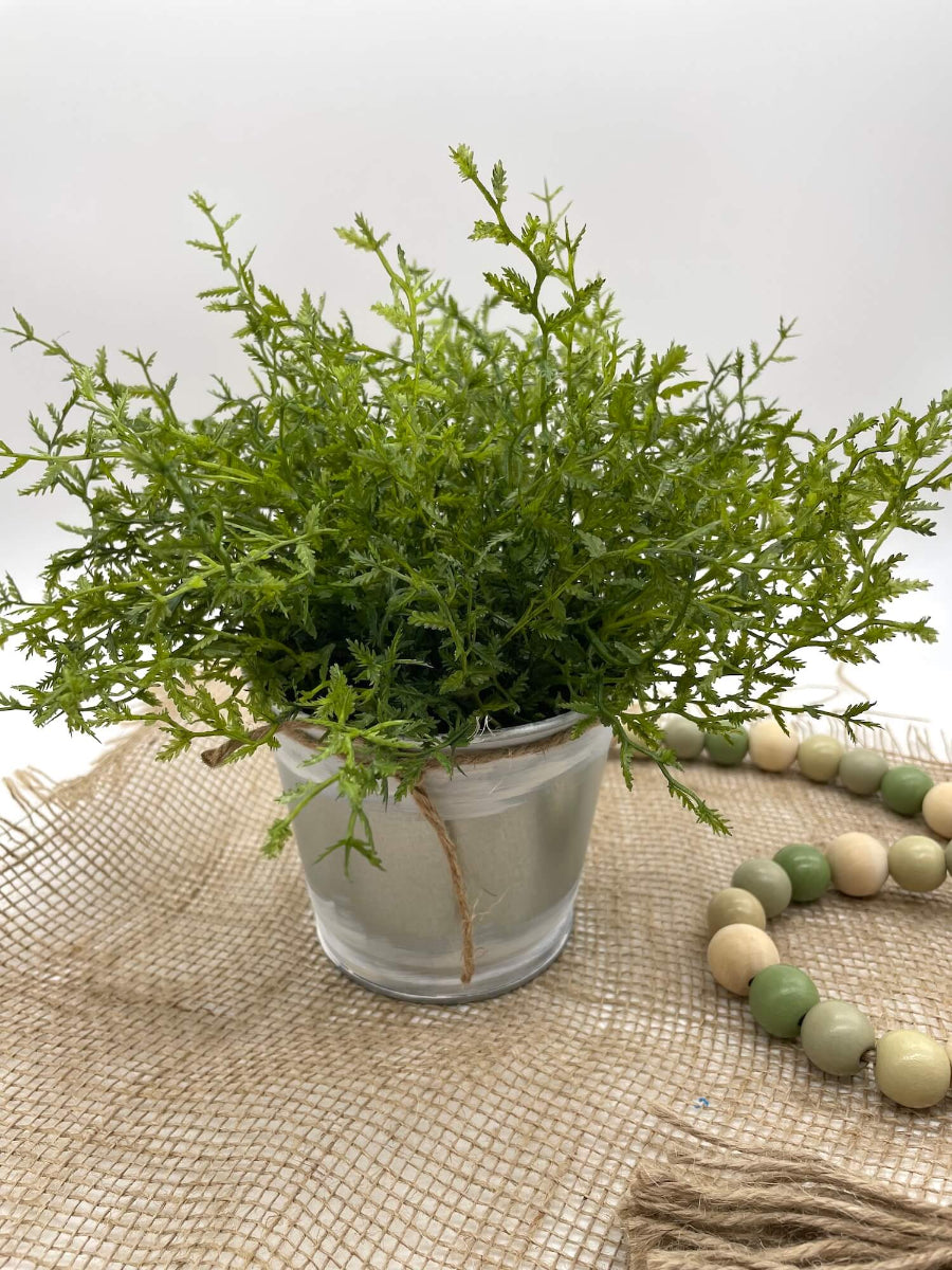 vivid green faux plant fern in metal pot touched with white paint and decorated with jute
