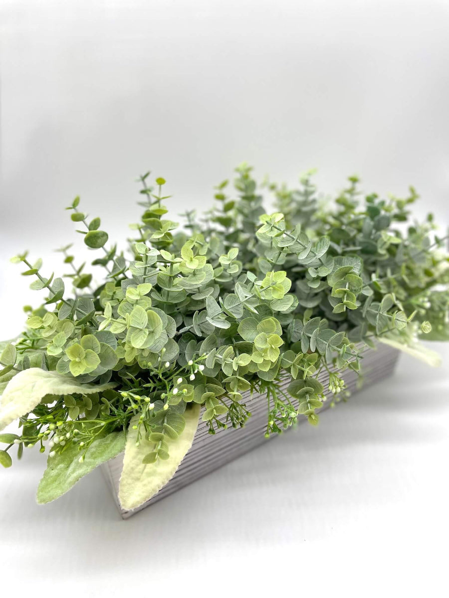 realistic looking faux eucalyptus with lambs ear leaves and delicate white flowers in whitewashed wooden planter box
