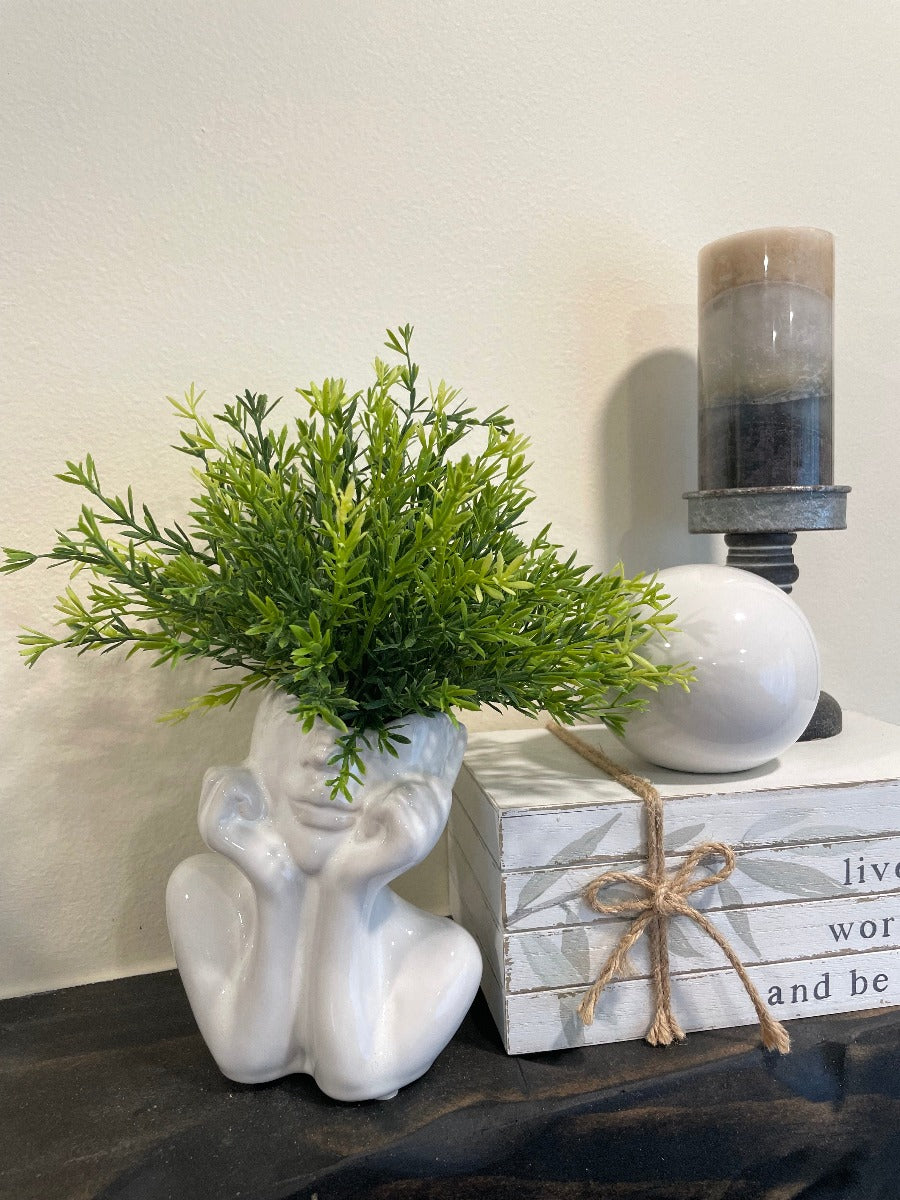 vivid green realistic looking faux plant in white ceramic woman head vase