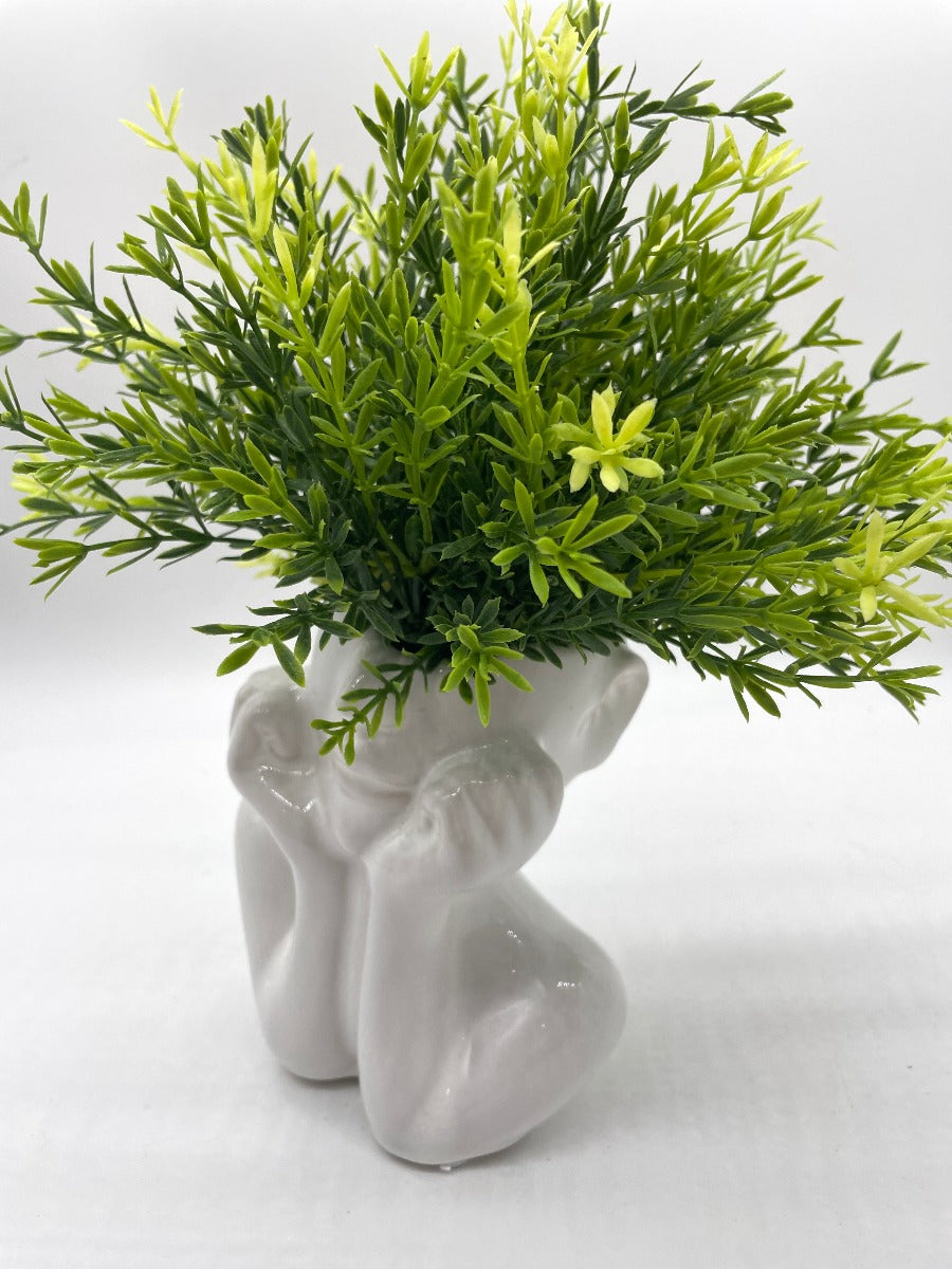 vivid green realistic looking faux plant in white ceramic woman head vase